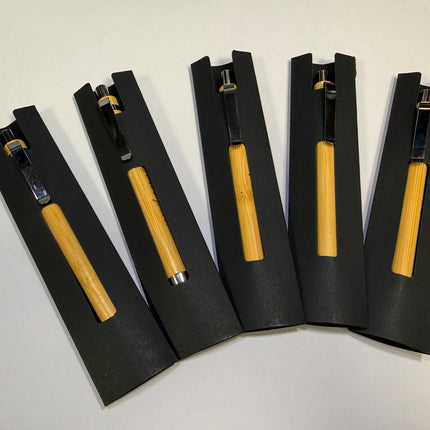 Five bamboo-handled tools with black metal heads, each resting in a black foam sleeve, arranged on a white surface.