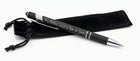 A black ballpoint pen with silver lettering that reads 'This Meeting Could've Been an Email!' resting on a black guitar headstock, with a black drawstring pouch beside it.