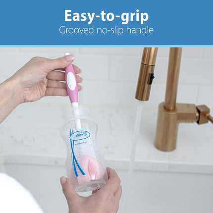 Person holding a cleaning brush with an easy-to-grip handle in a bathroom setting.