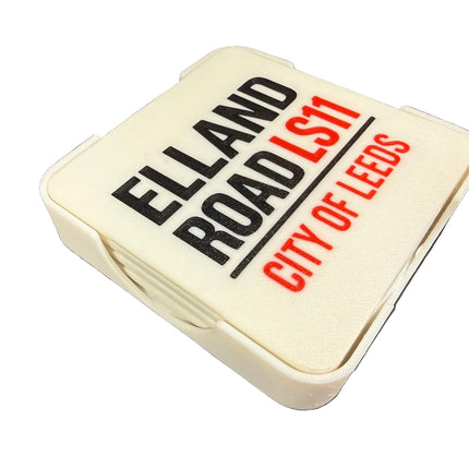 A square white car windscreen wash cover with 'ELLAND ROAD LS11 CITY OF LEEDS' printed on it, shown on a dark background.