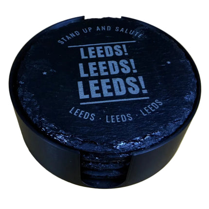 A round black plastic container with a printed lid reading 'LEEDS! LEEDS! LEEDS!' in white, placed on a light wood-grained tabletop.