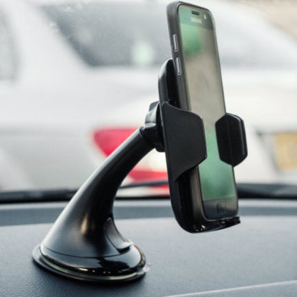 A black car windshield suction mount holding a smartphone, shown attached to a car dashboard with a blurred vehicle in the background.