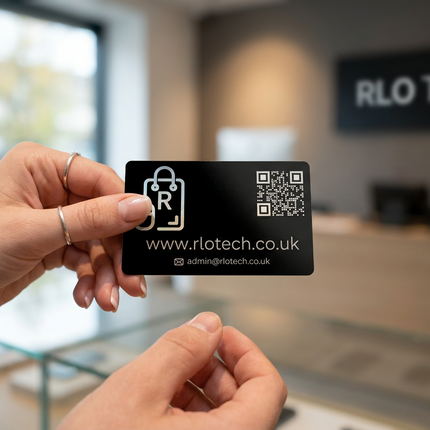 A person holds a black RLO Tech business card in front of a blurred retail store interior. The card features a white shopping bag with an 'R' logo, QR codes, and the website www.