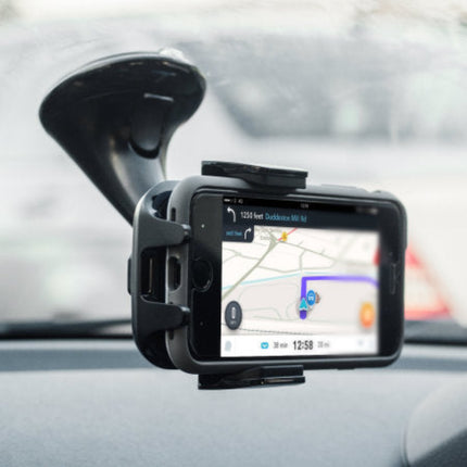 A black car windshield-mounted GPS tracker with a suction cup holder, shown attached to a dashboard with a smartphone displaying a navigation map.